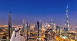 Arabian man watching night cityscape of Dubai.