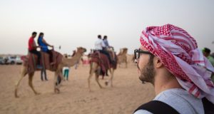 An Arabian man watching camels at desert safari.