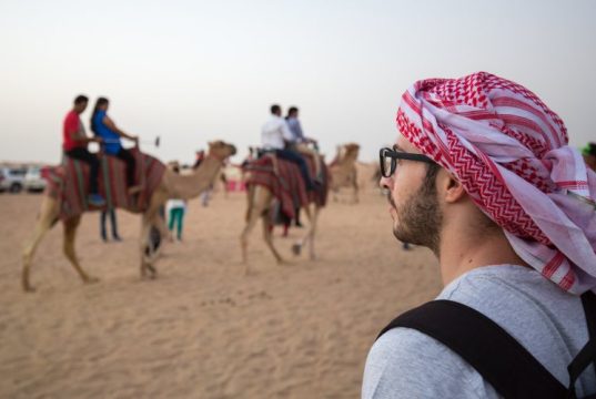 An Arabian man watching camels at desert safari.