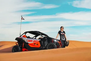 Woman standing beside a dune buggy on a Dubai desert safari adventure