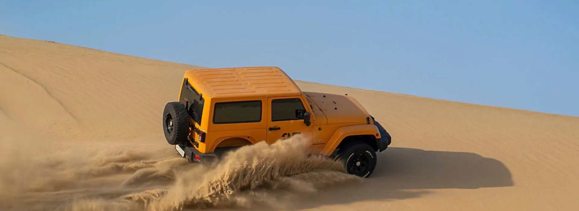 Yellow 4x4 jeep driving on sand dunes during Abu Dhabi Morning Desert Safari adventure