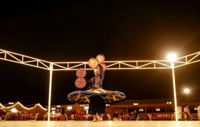 Live cultural performance during an overnight desert safari in Dubai, featuring traditional dance and entertainment under the night sky.