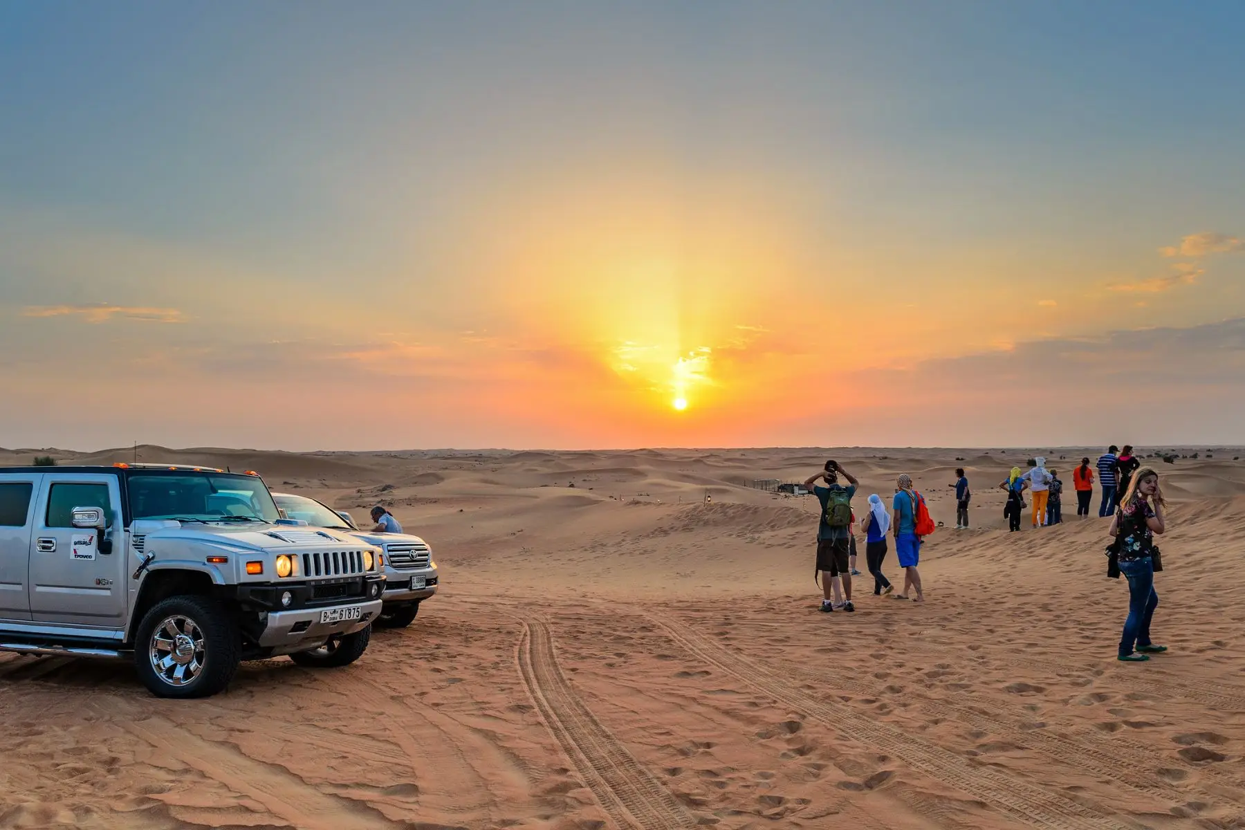 Morning Desert Safari in Dubai with sunrise and people walking in the desert
